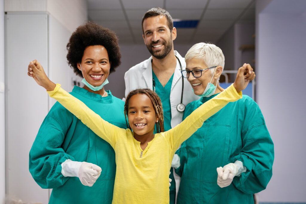 Friendly pediatricians and happy smiling girl patient in hospital